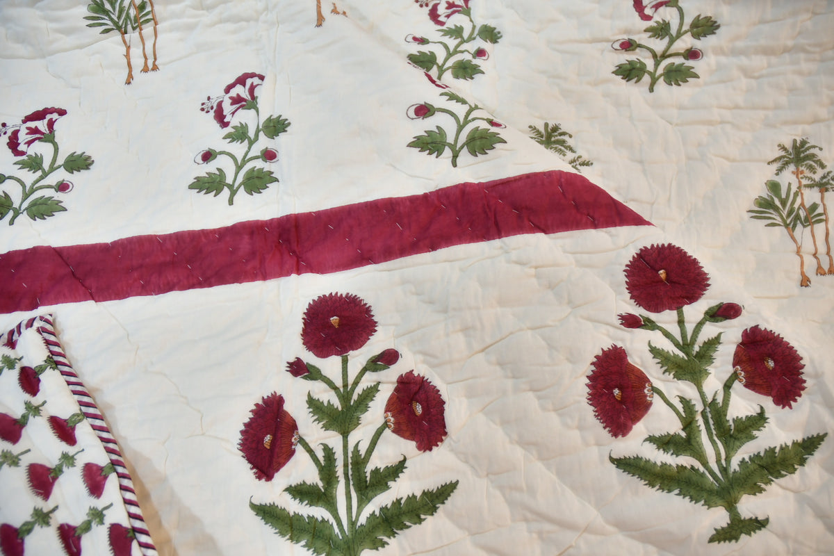 Quilt with floral patterns and a red strip on a white background