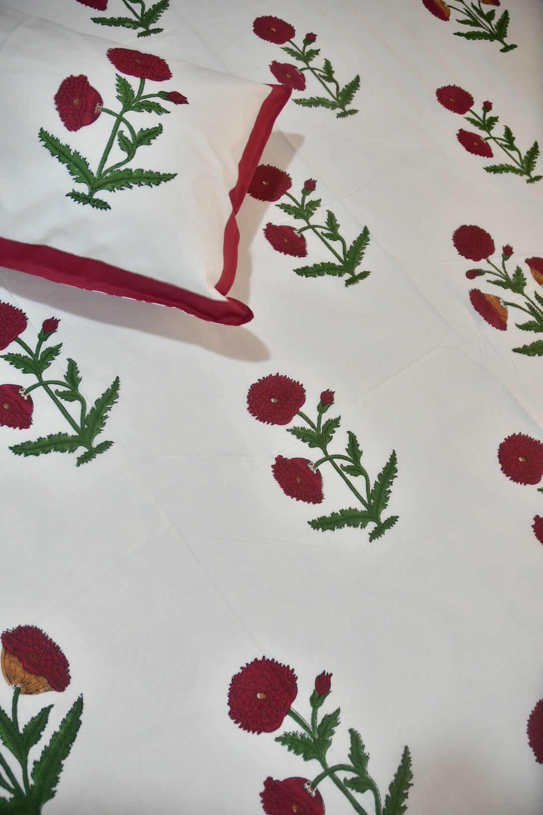 Floral patterned fabric with red flowers and green leaves on a white background