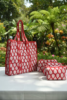 Red and white patterned tote bag on a bed with floral bedding