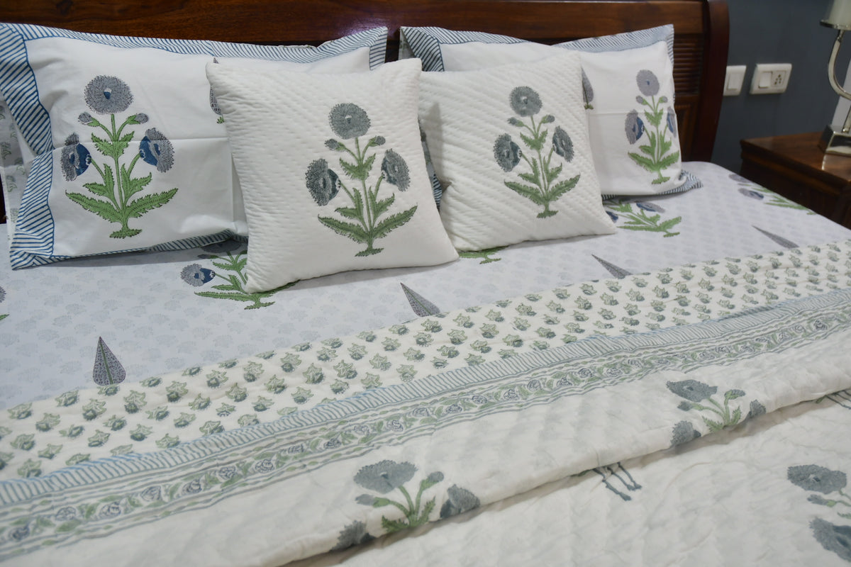 Floral-patterned bedspread and pillows on a bed in a bedroom setting.