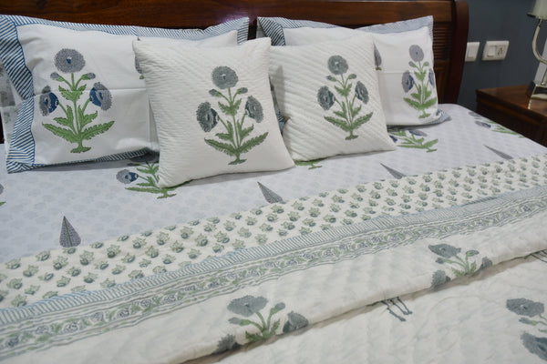 Floral-patterned bedspread and pillows on a bed in a bedroom setting.