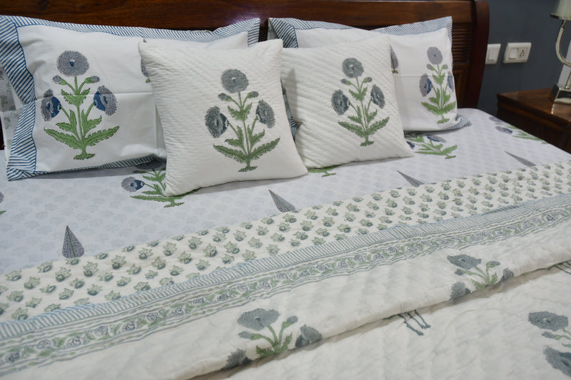 Floral-patterned bedspread and pillows on a bed in a bedroom setting.