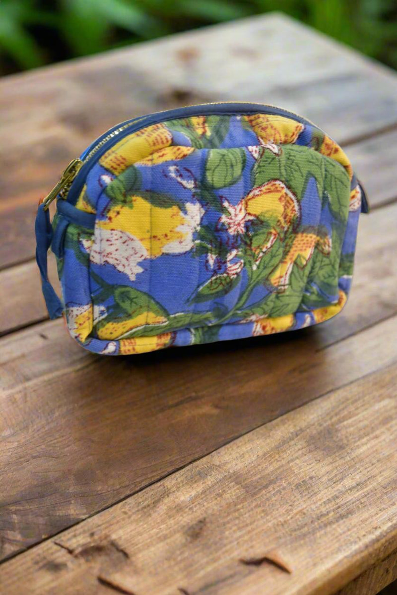 Floral-patterned pouch on a wooden surface with greenery in the background