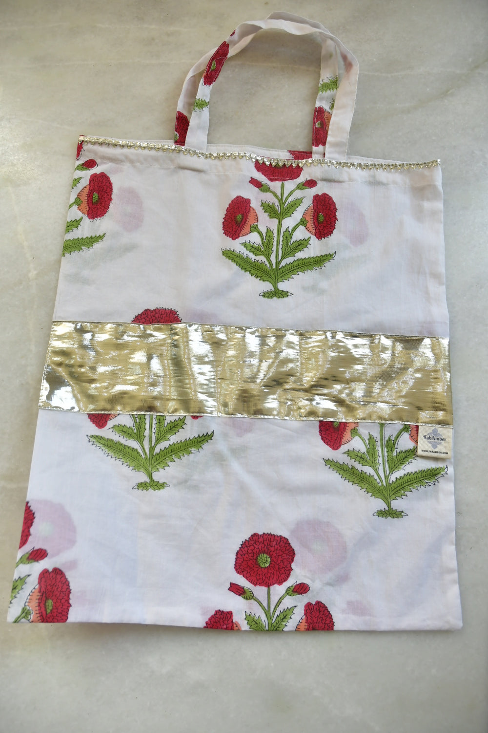 Floral-patterned fabric bag with a metallic strip on a light background