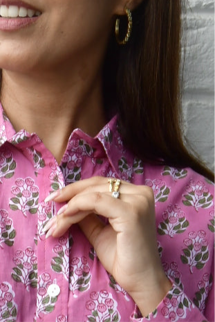 Close-up of a person wearing a pink floral shirt with a neutral background