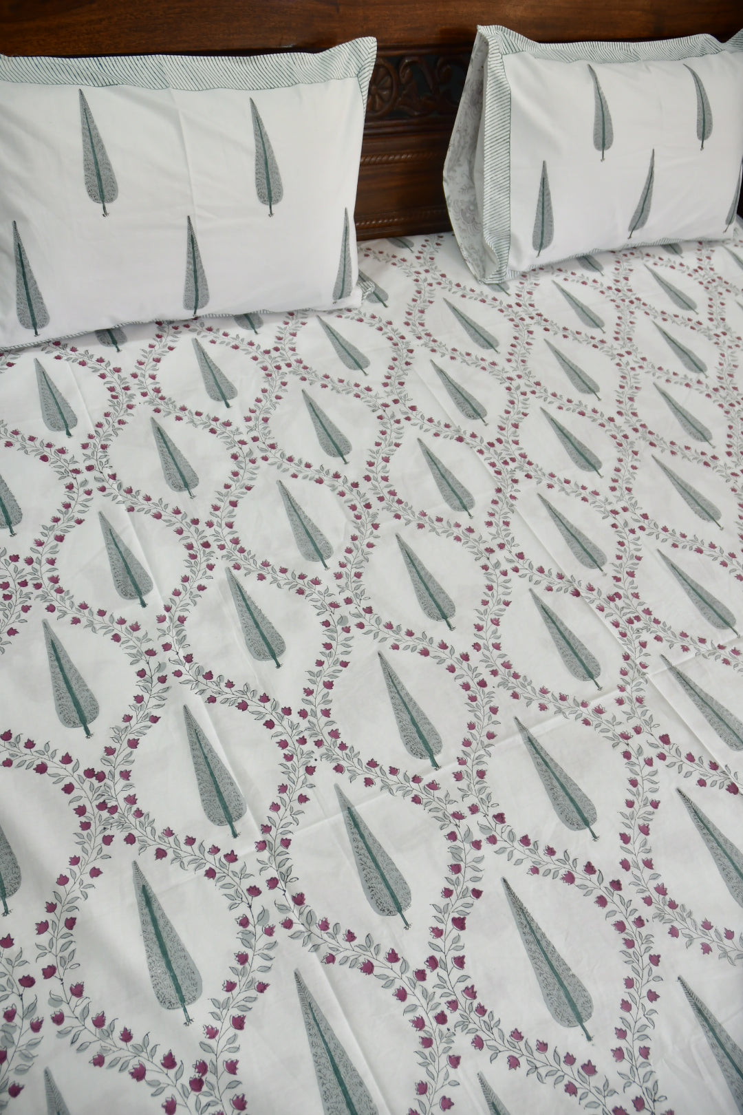 Bedspread with floral jaal pattern and matching pillows on a bed.