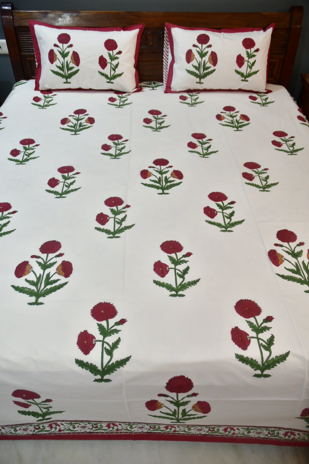 Bedspread with floral pattern and matching pillows on a bed.