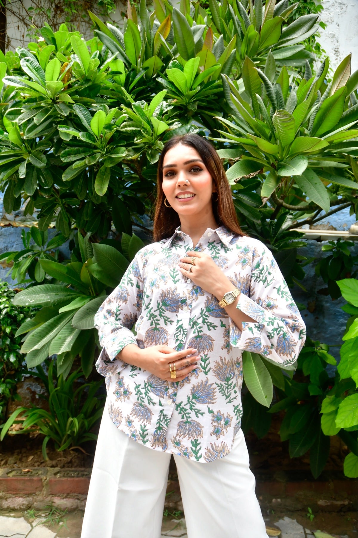 Woman standing outdoors with green foliage in the background