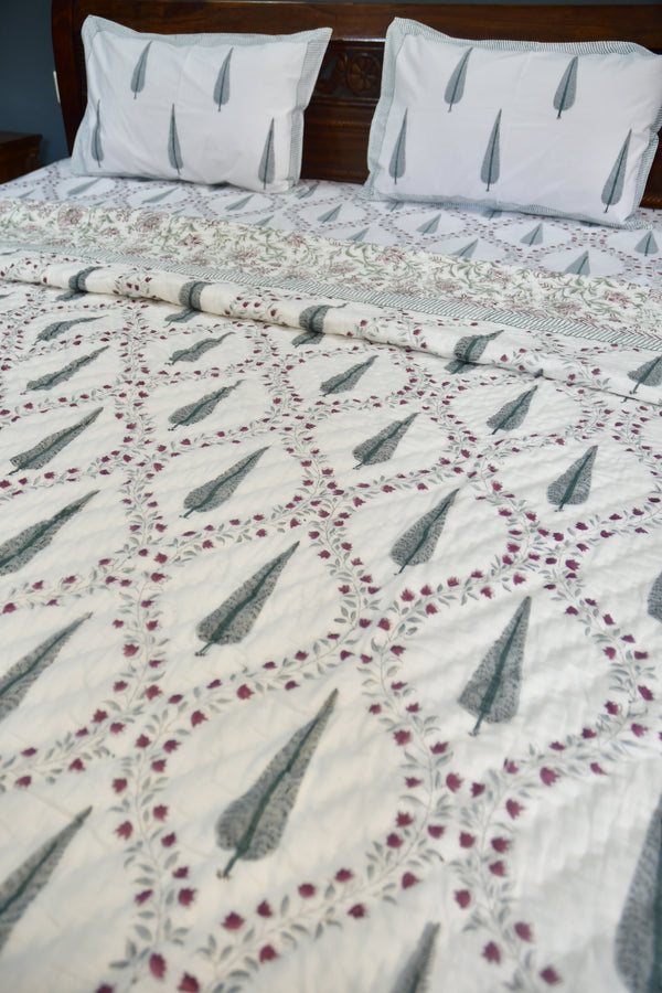 Floral patterned quilt with pillows on a wooden surface