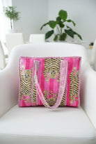 Pink bag with gold tiger design on a white chair