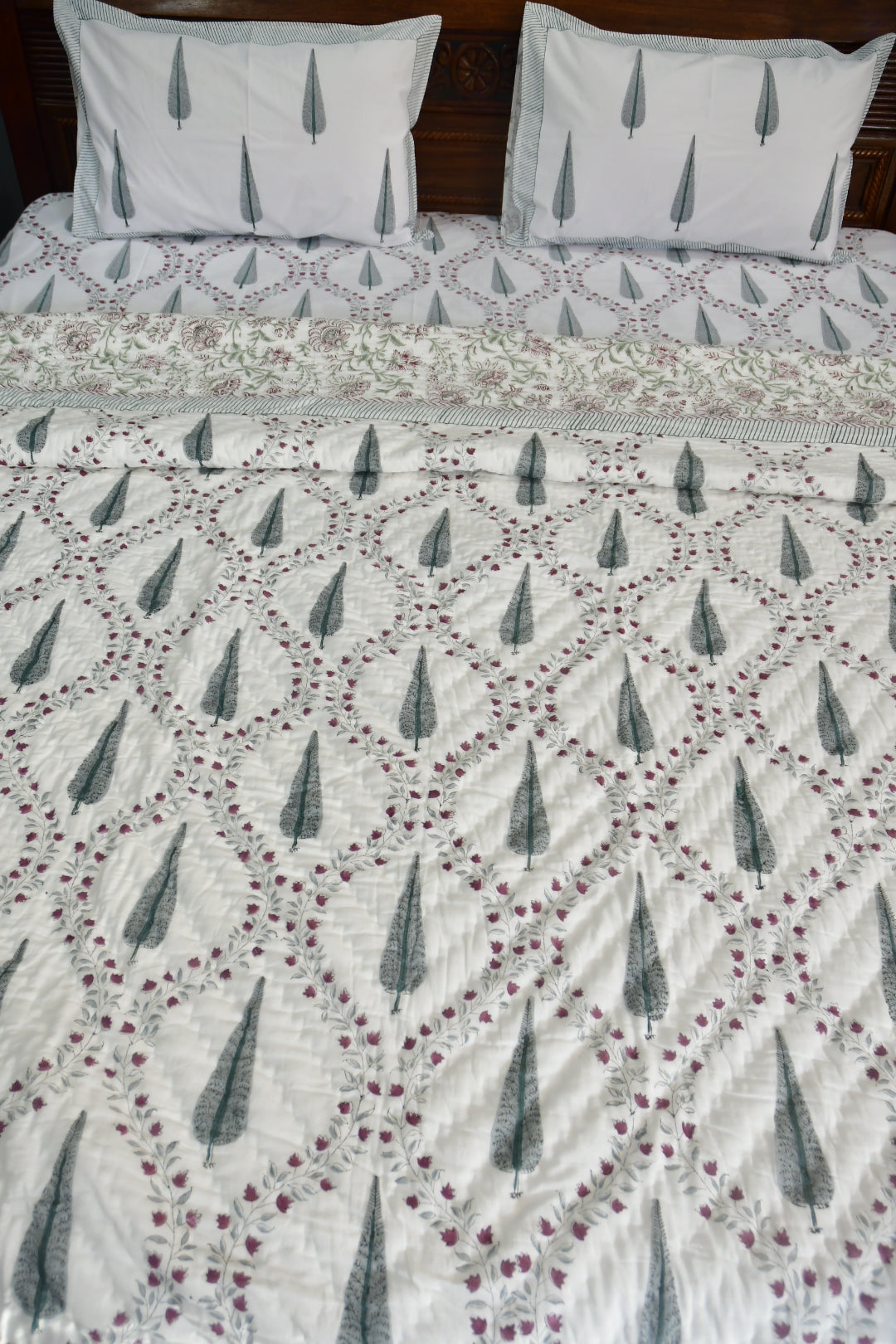 Quilt with geometric pattern on a bed with matching pillows.
