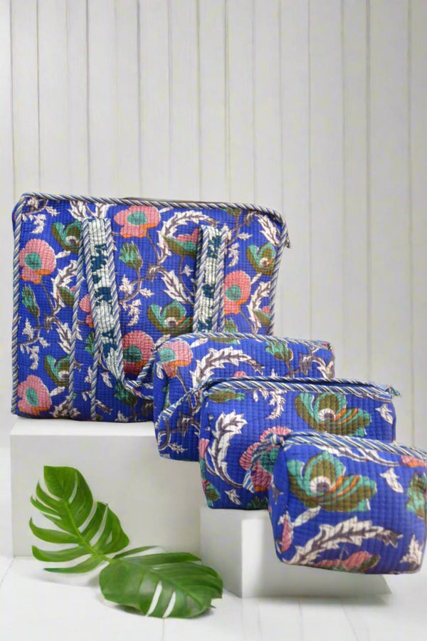 Set of three blue floral-patterned pouches on a white surface with a leaf decoration.