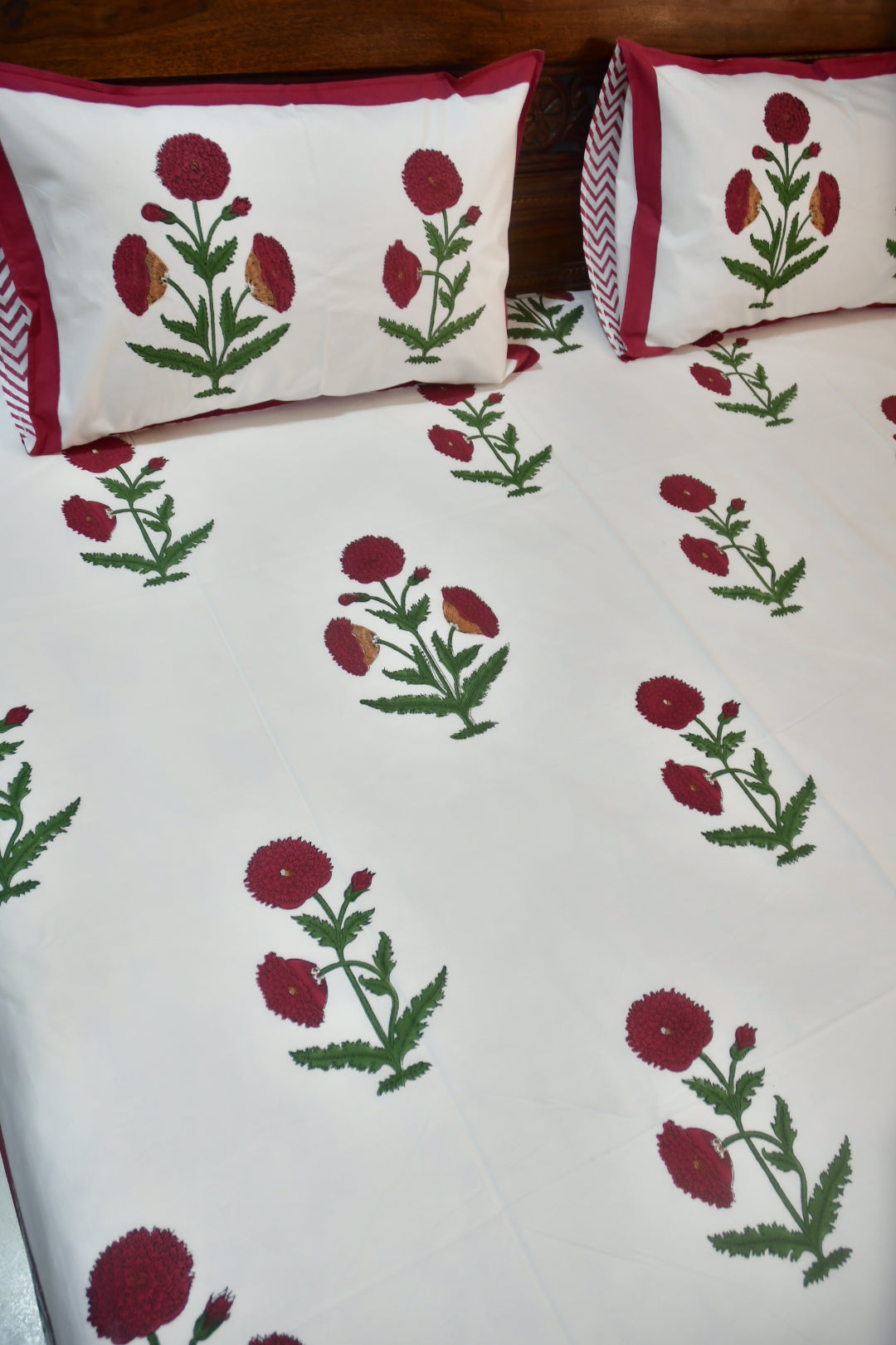 Floral patterned fabric with red flowers and green leaves on a white background
