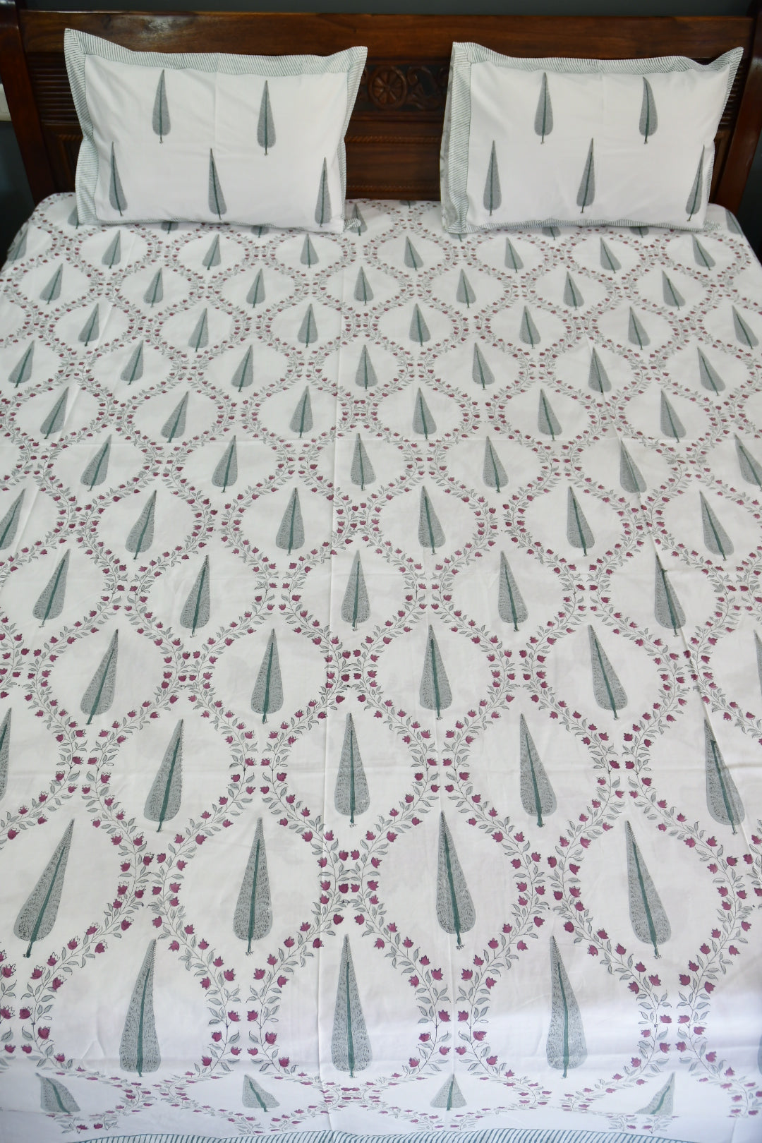 Bed with a patterned quilt and white pillows on a wooden bed frame.