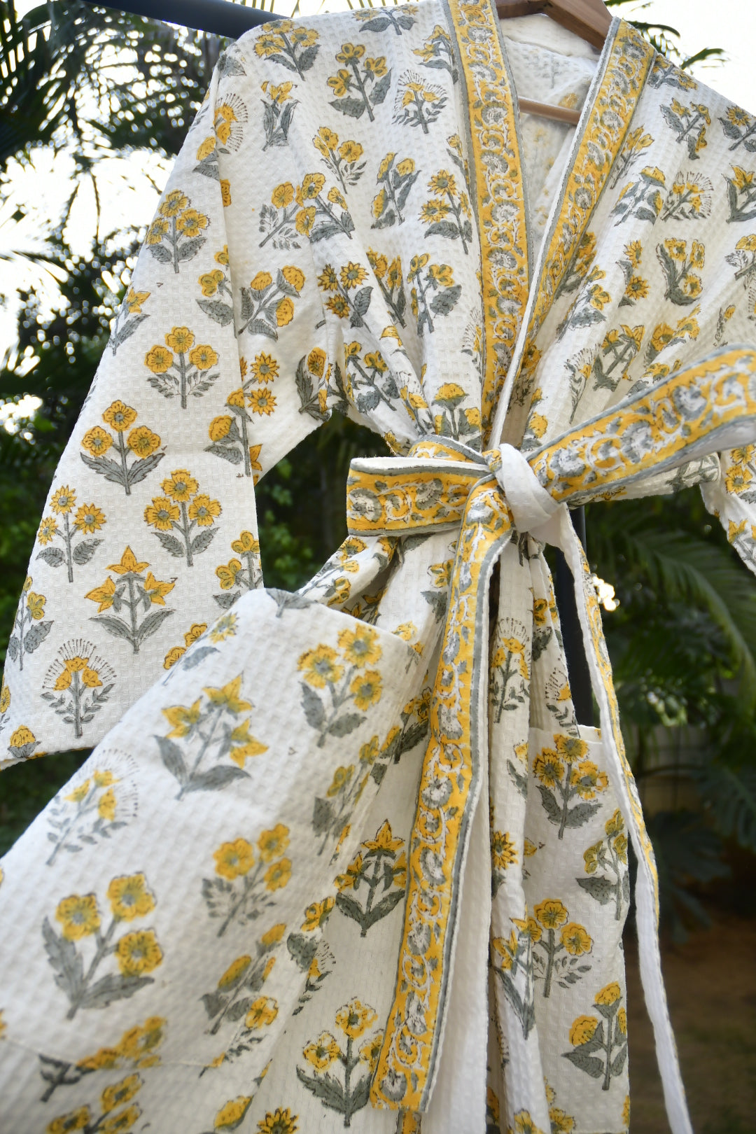 Floral-patterned fabric with yellow and gray flowers on a white background, tied together.