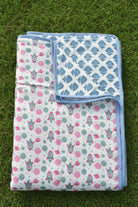 Two patterned blankets on a grassy surface