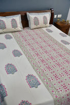 Bed with floral patterned bedspread and pillows in a bedroom setting.