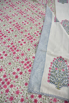 A close-up of a white fdohar with an all-over pink floral print and a decorative border featuring blue stripes and a blue-and-pink tree motif.