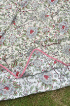 Floral patterned AC comforter with red and green accents on a grassy background