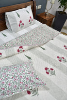 Floral patterned bedspread on a bed with matching pillows in a bedroom setting.