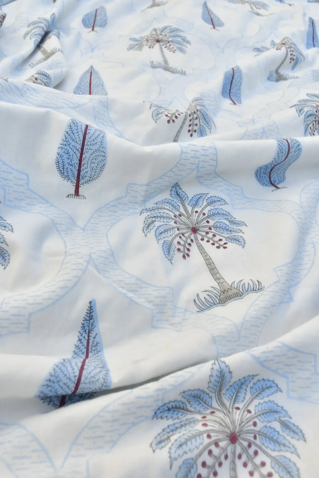Close-up of fabric with embroidered palm tree and leaf patterns on a white background