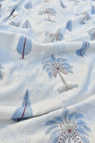 Close-up of fabric with embroidered palm tree and leaf patterns on a white background