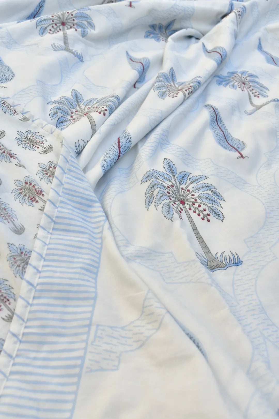 Embroidered palm tree pattern on a light blue and white fabric