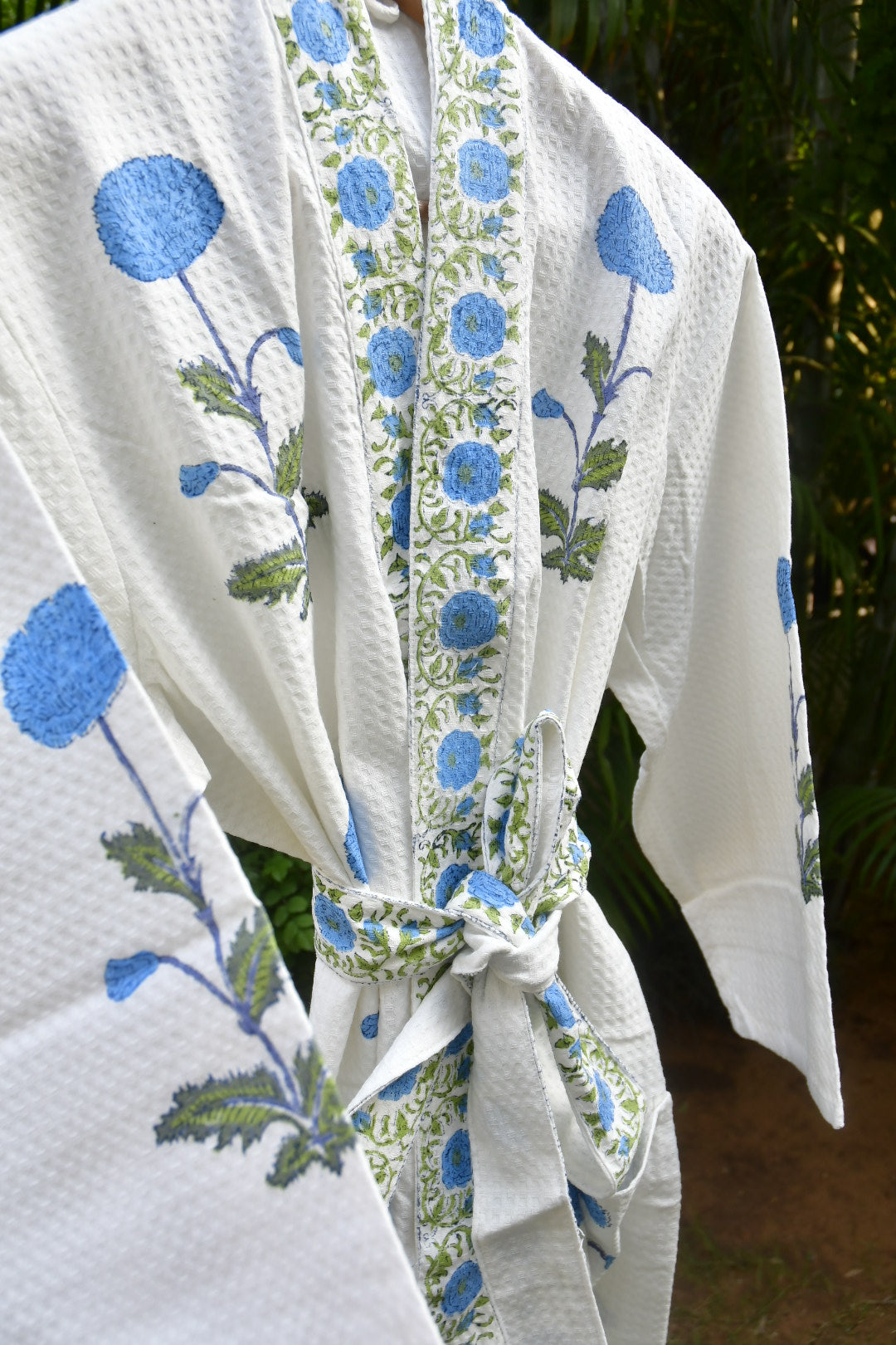White bathrobe with blue floral patterns, tied into a bow outdoors.