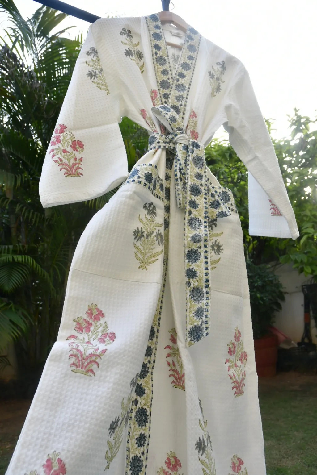 White embroidered robe with floral patterns hanging outdoors.