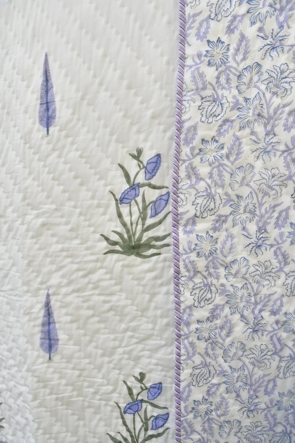 Close-up of a quilt with floral patterns and embroidery on a white background