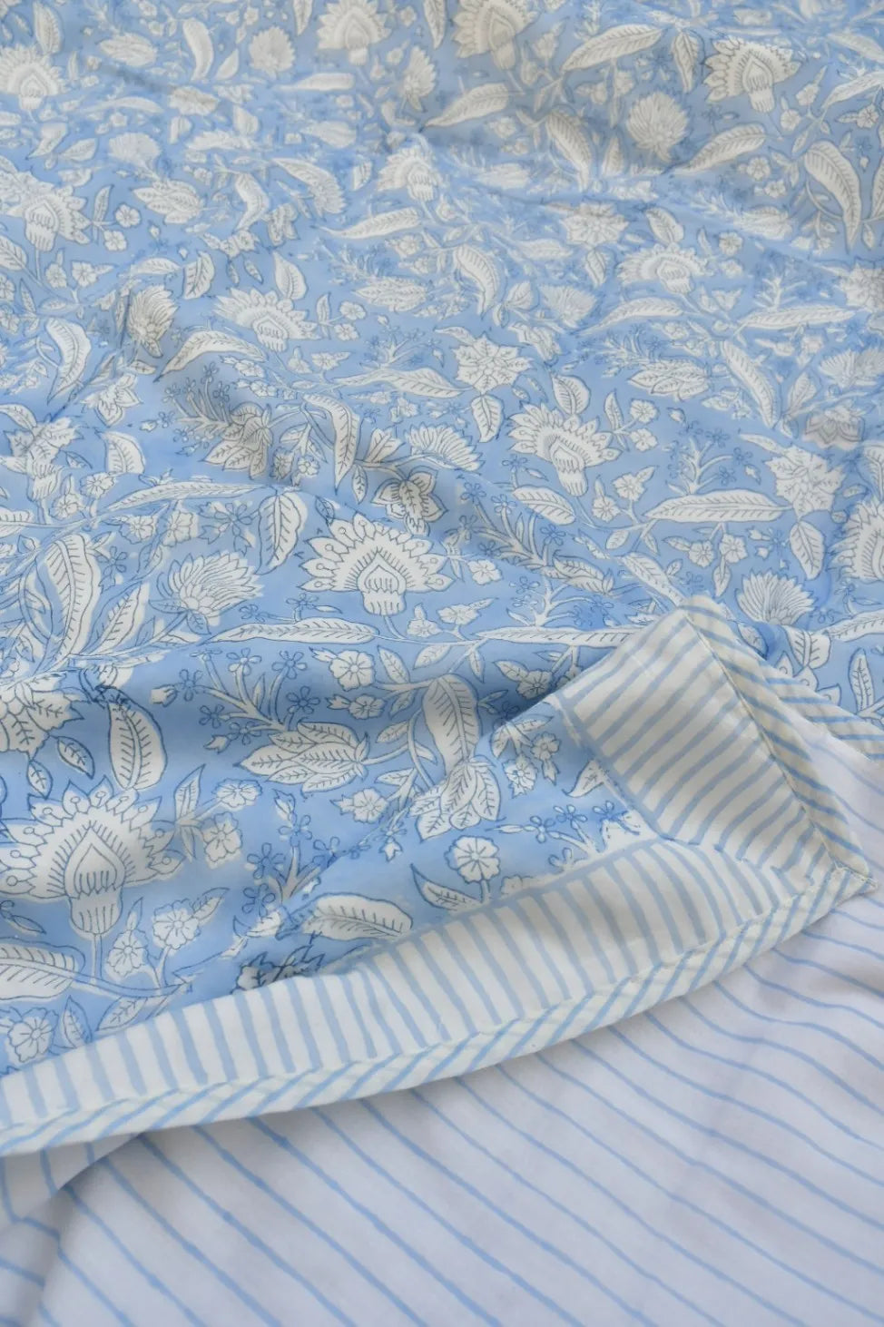 Close-up of blue floral fabric with a striped pattern underneath