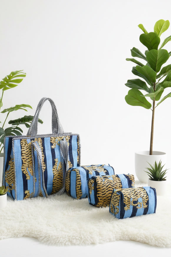 Striped bag and cylindrical container on a white surface with plants in the background