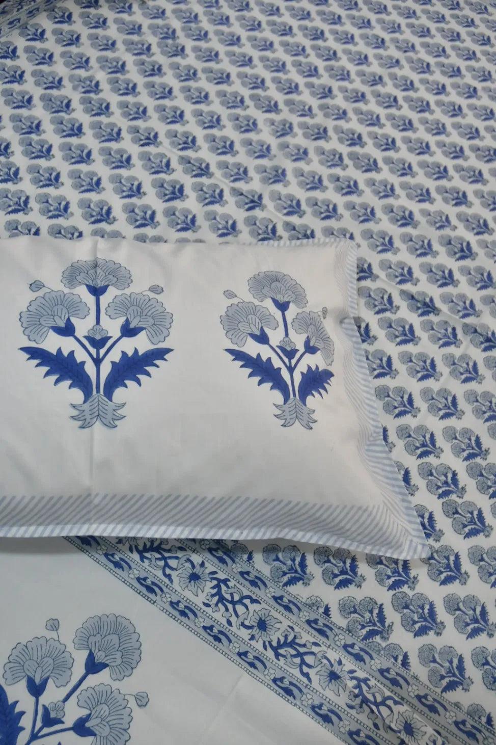 Blue floral patterned bedsheet with a pillow on top