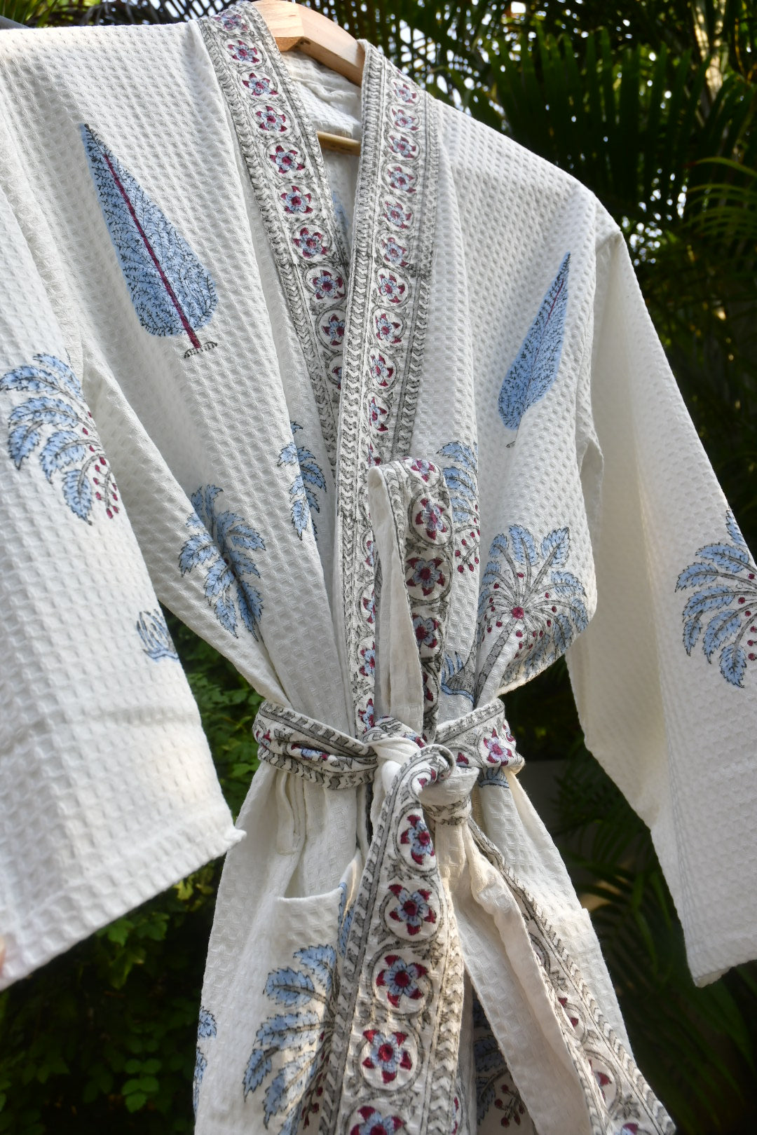 Close-up of a fabric with floral patterns and decorative ribbons against a natural background.