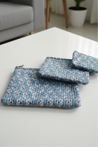 Set of blue floral-patterned pouches on a white surface with a blurred background