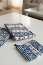 Two patterned pouches on a white surface with a blurred background