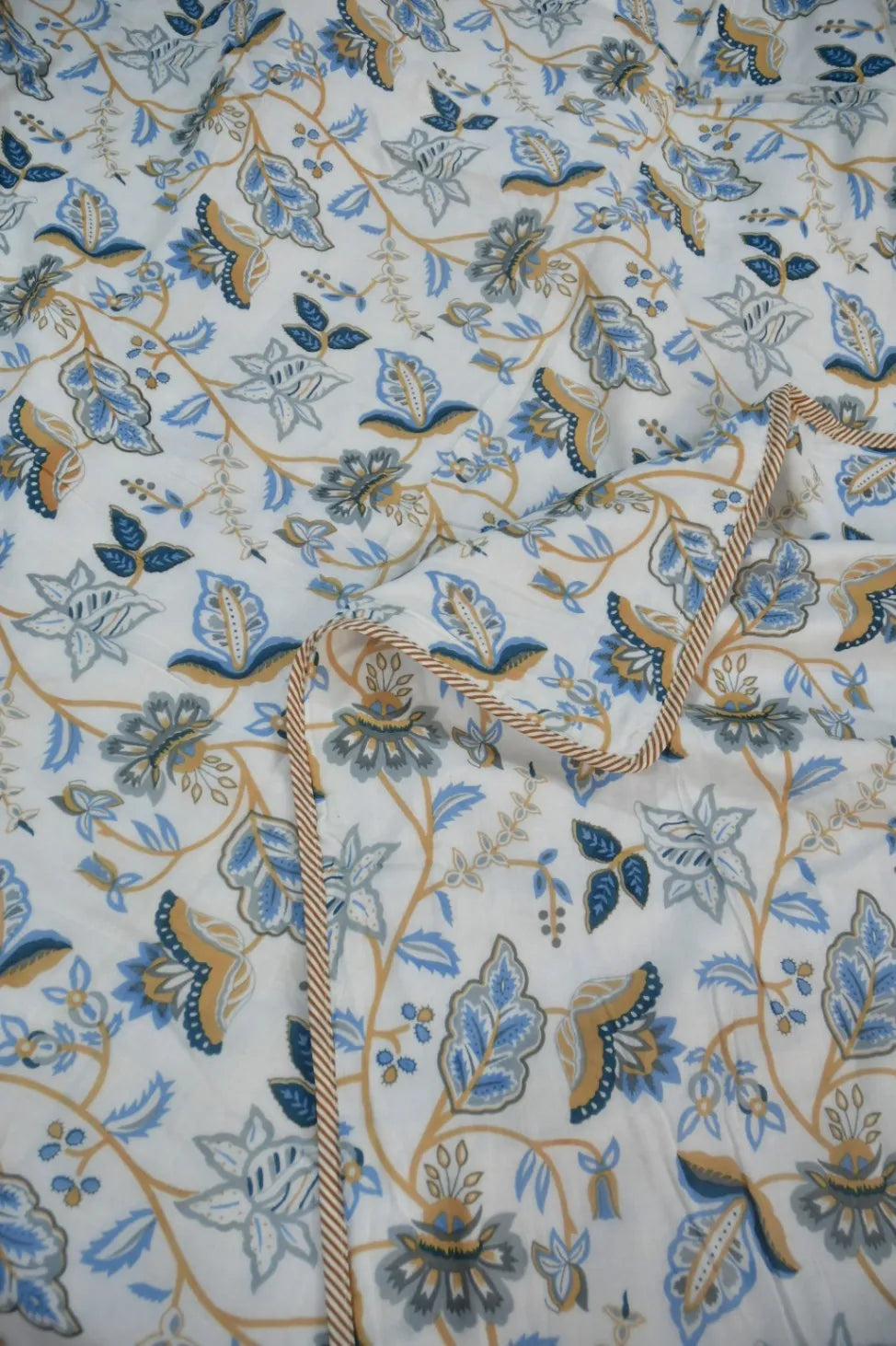 Close-up of floral Dohar with blue, green, and beige patterns on a white background