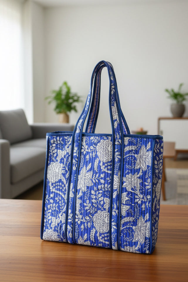 Blue and white floral patterned tote bag on a wooden surface with a blurred indoor background