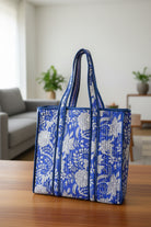 Blue and white floral patterned tote bag on a wooden surface with a blurred indoor background