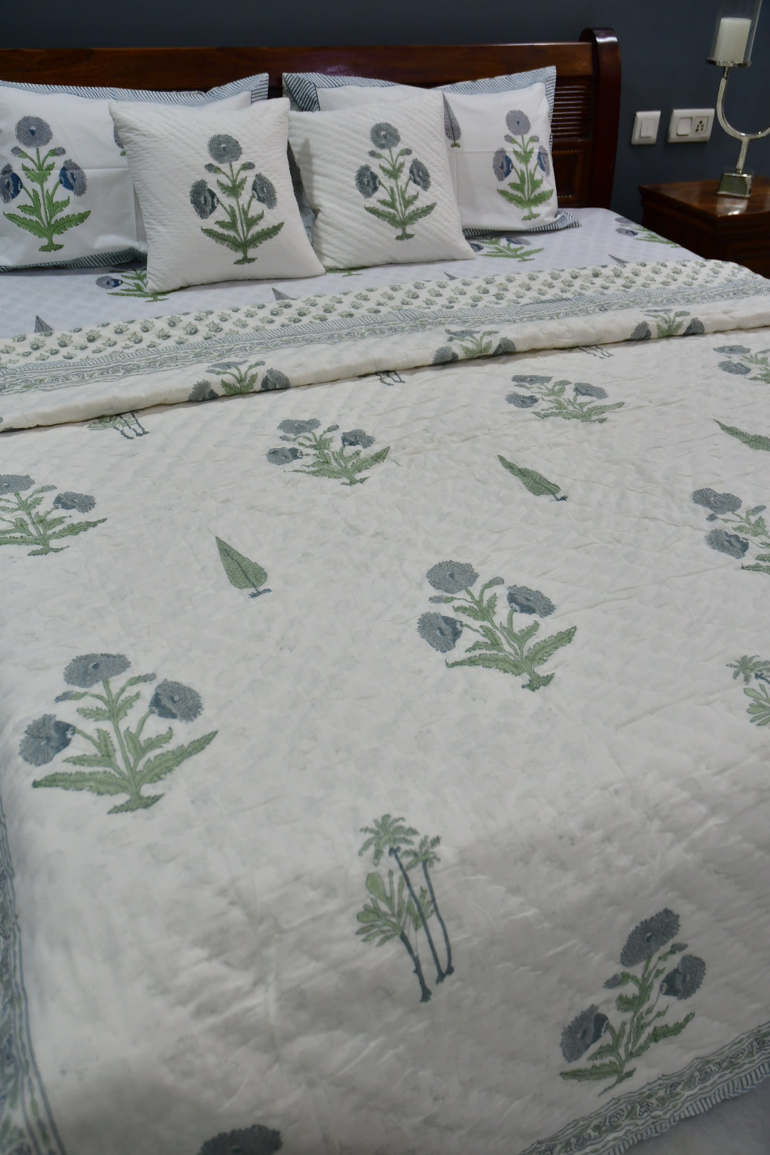 Bedspread with floral pattern and matching pillows on a bed.