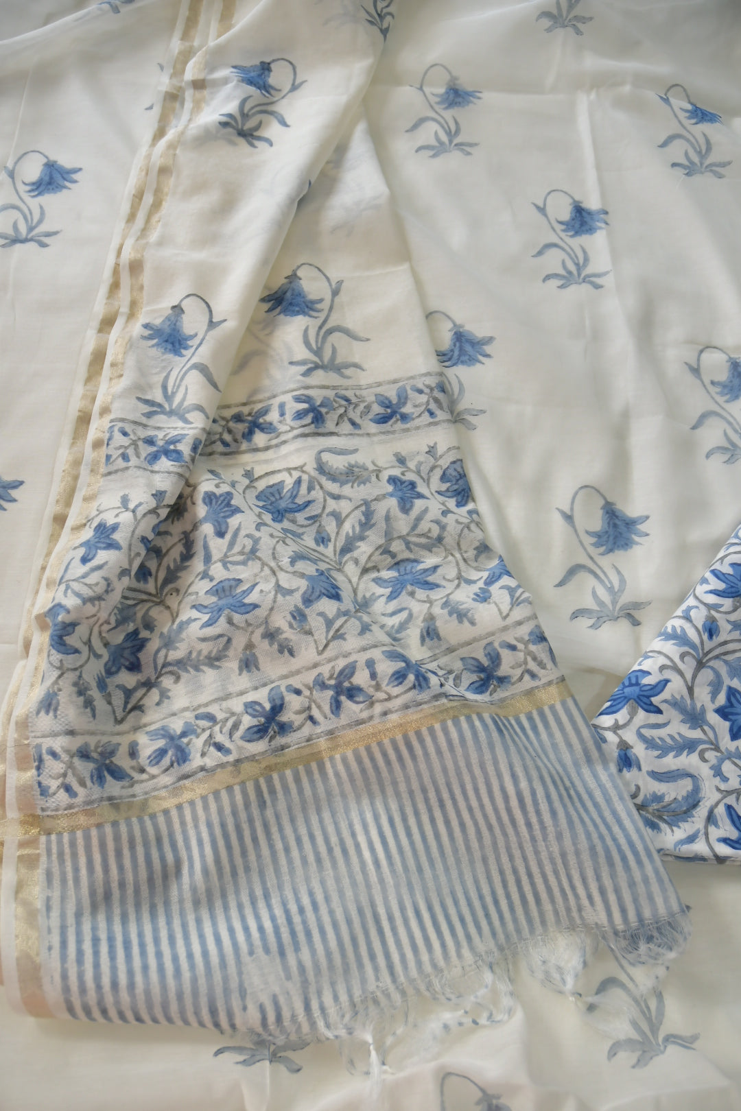 White fabric with blue floral patterns and a striped border.