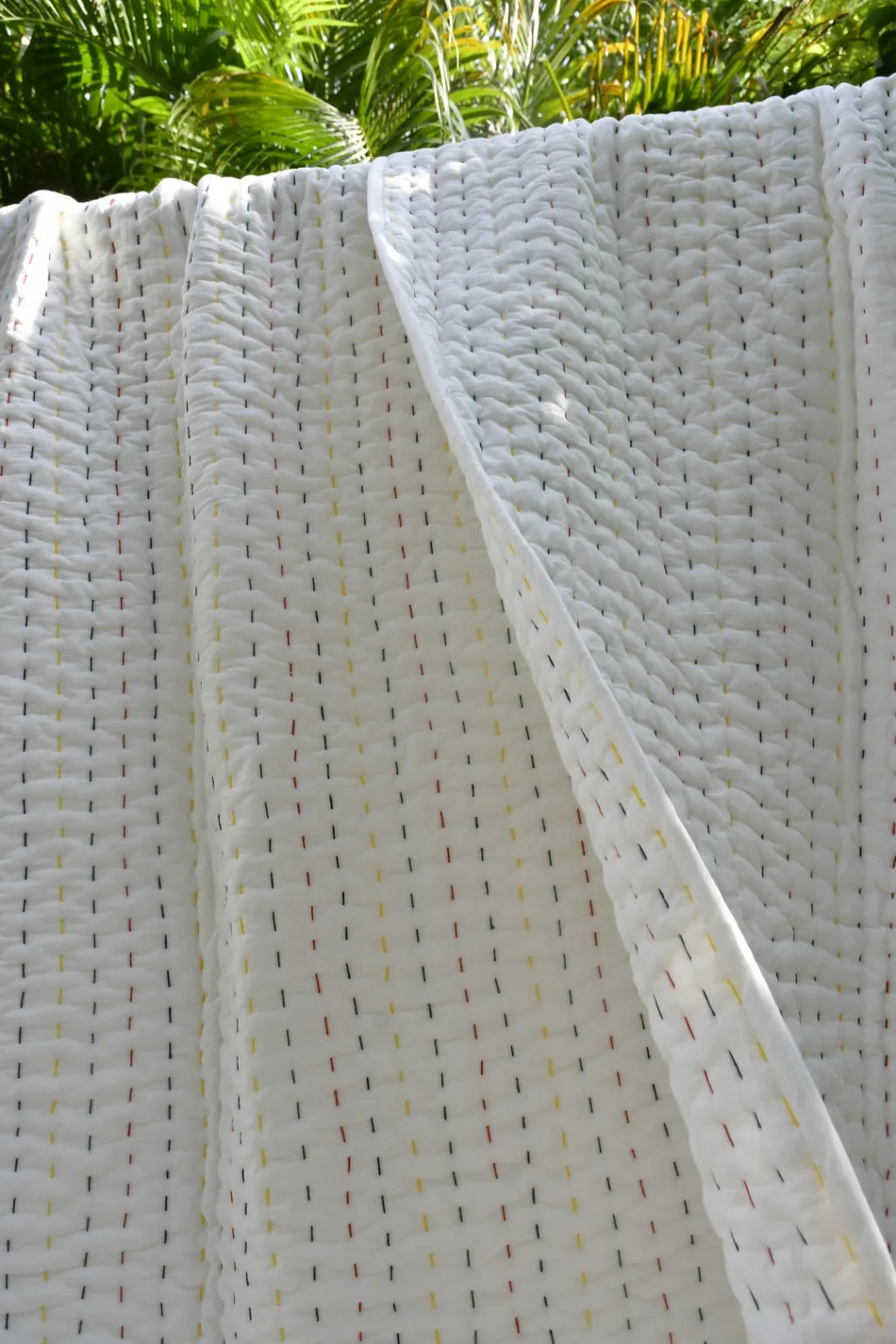 Close-up of a white woven quilt with a subtle pattern, possibly outdoor furniture or a decorative panel.