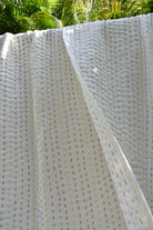 Close-up of a white woven quilt with a subtle pattern, possibly outdoor furniture or a decorative panel.