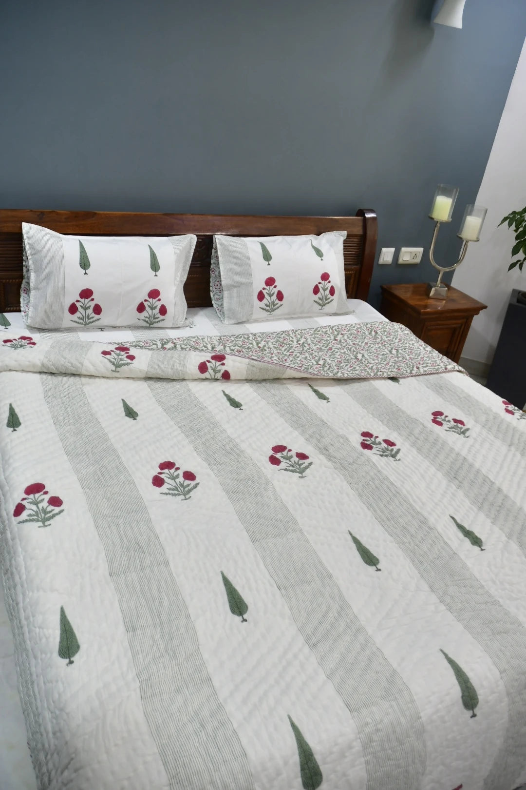Bed with floral patterned bedding against a gray wall.