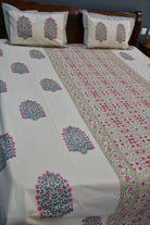 Floral patterned bedsheet on a bed with matching pillows.