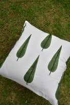 White pillow with green leaf patterns on a grassy background