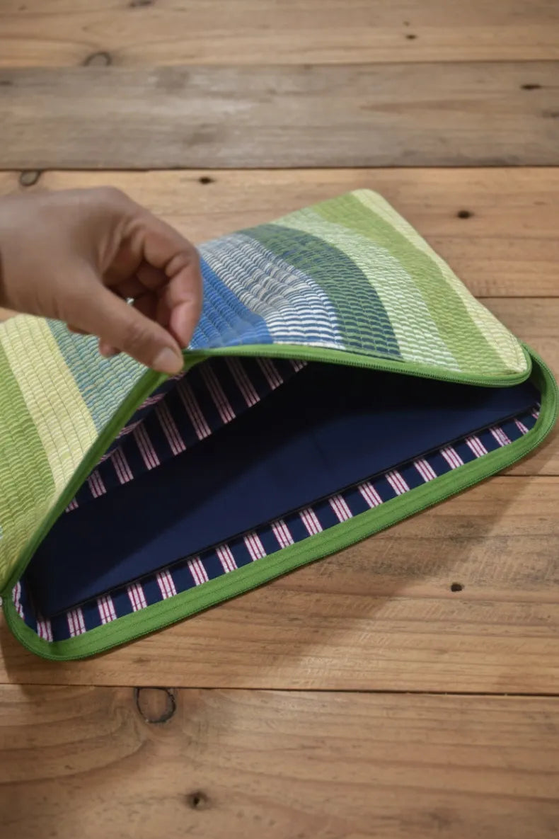 Hand holding a colorful woven fabric on a wooden surface . Laptop sleeve