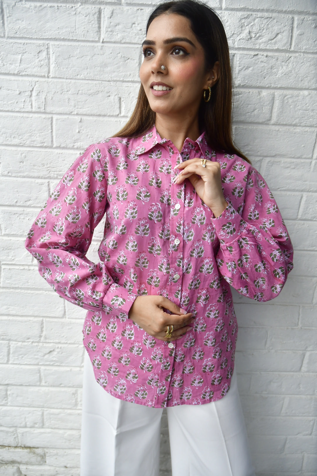 Woman wearing a pink floral blouse on a white brick wall background