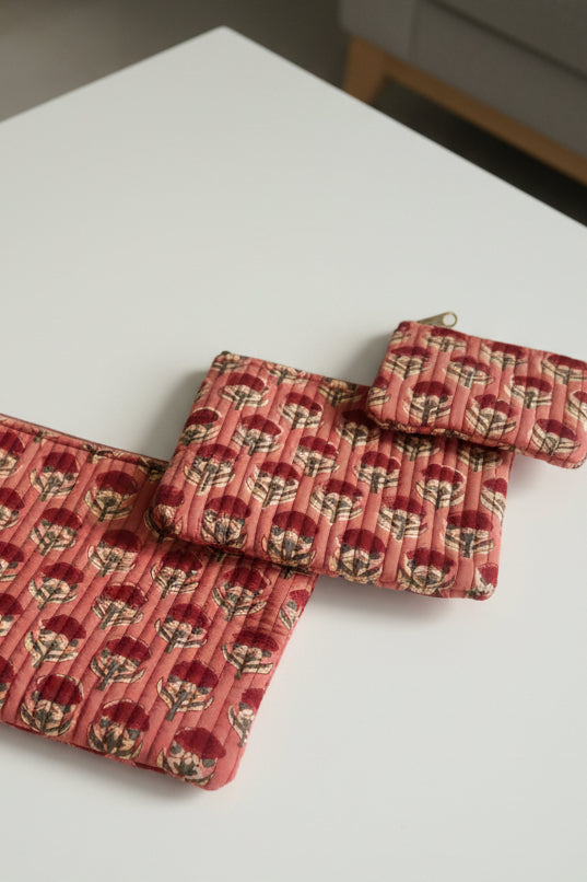 Two red patterned pouches on a white surface