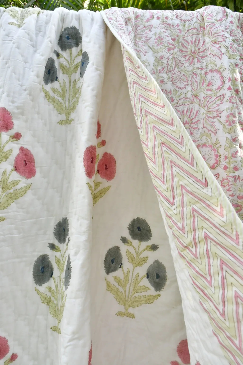 Floral and geometric patterned fabric with pink flowers and green leaves on a white background.